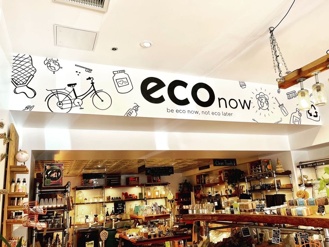 Inside an eco now refill store — shelves of bulk and refillable products beneath the eco now mural